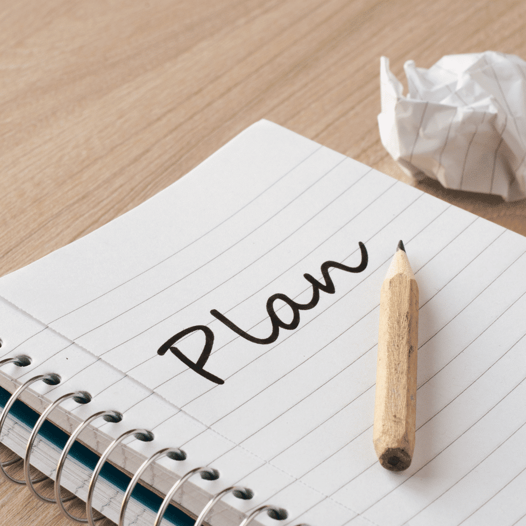 Spiral-bound notebook with the word 'Plan' written on it, accompanied by a pencil.