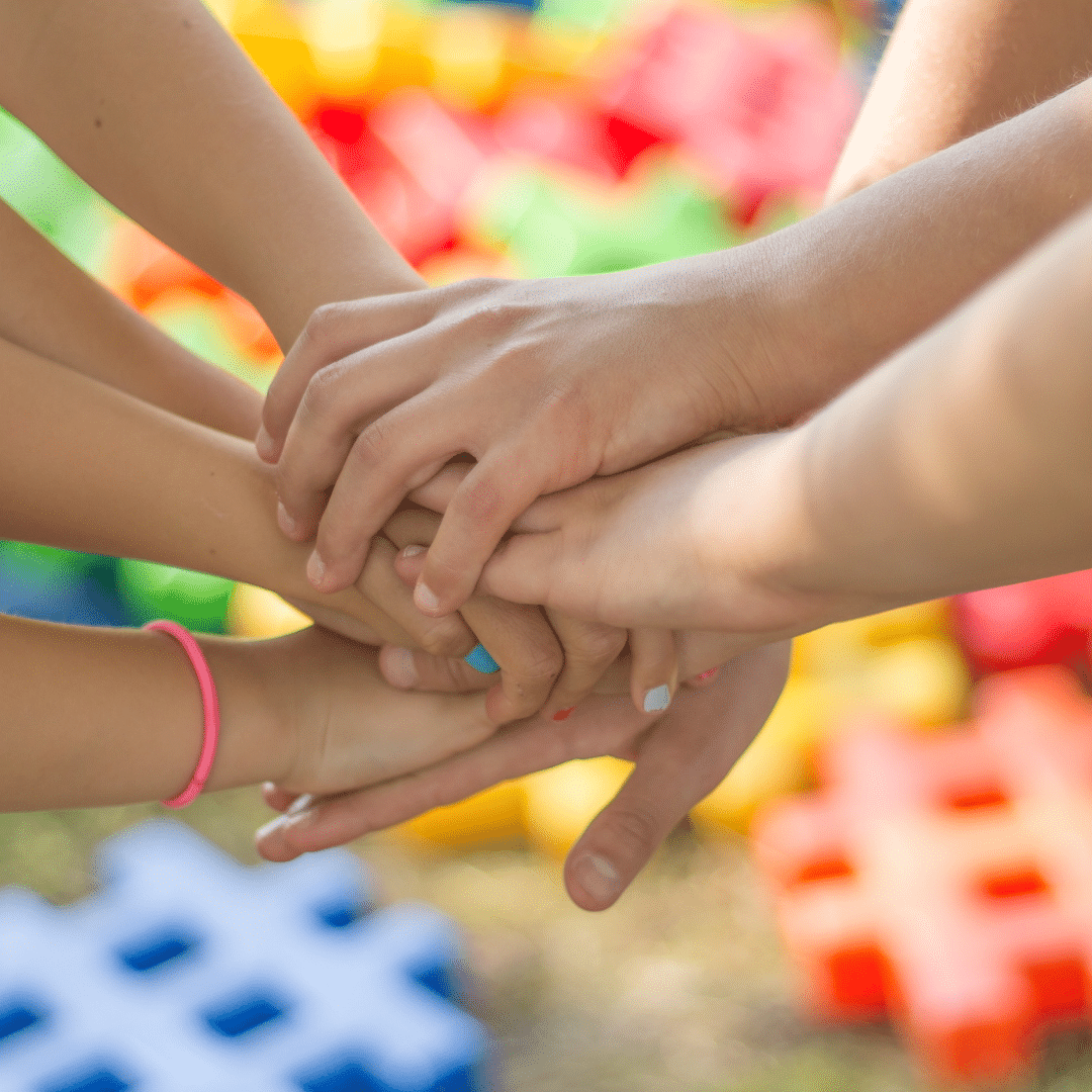 Hands overlapping in the middle of a circle, symbolizing collaboration and unity